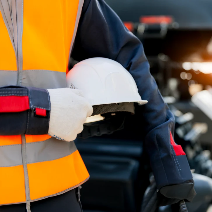Chantier de construction extérieur avec trois ouvriers portant casques de sécurité jaunes et lunettes de protection
